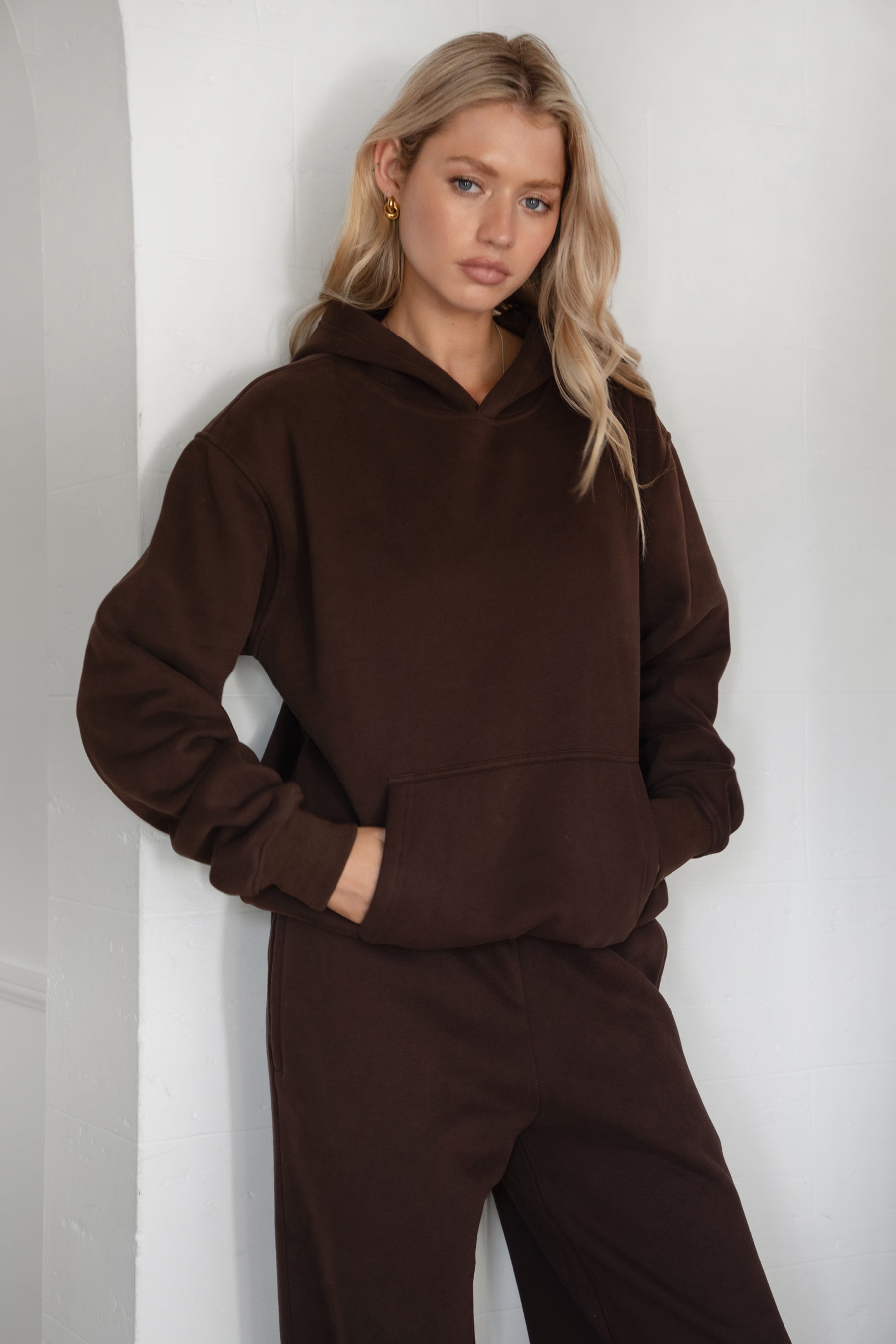 Woman wearing a brown hoodie and pants against a white background