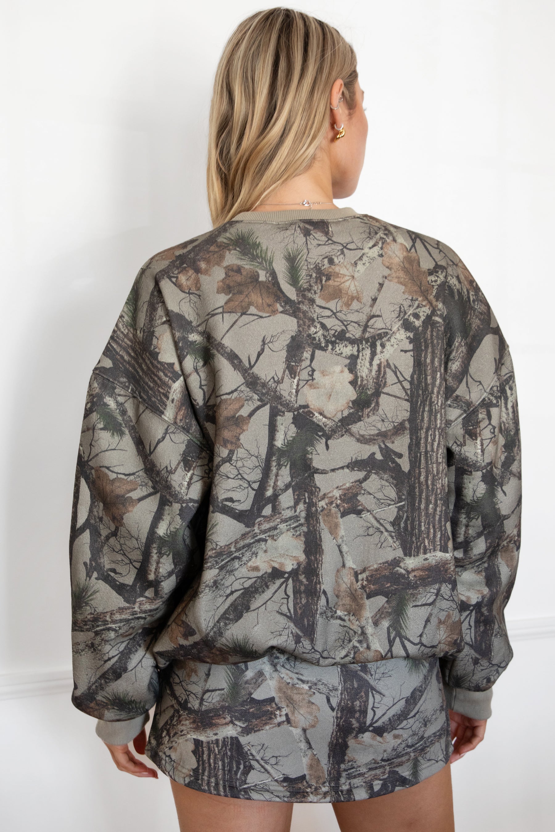 Person wearing a camouflage outfit against a white background